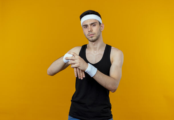 手腕戴着头巾的年轻运动型男子抚摸着手腕 把手伸到橘子上男人伸展头带