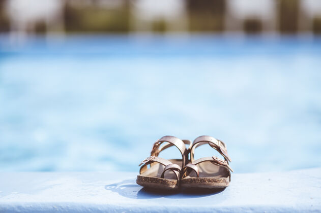 一天特写镜头聚焦皮革凉鞋躺在泳池边放松休闲游泳池