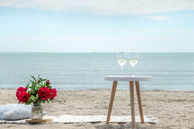 浪漫带着鲜花和香槟的海边浪漫野餐度假的概念浪漫休息大海