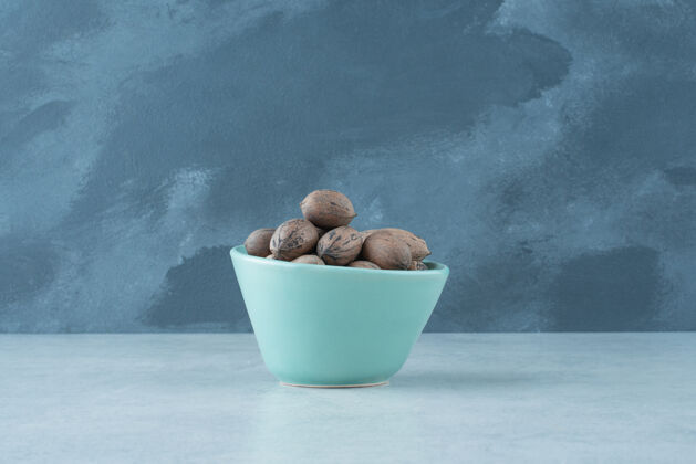 可口在大理石背景上放满坚果的蓝色小盘高质量照片小食物蓝色