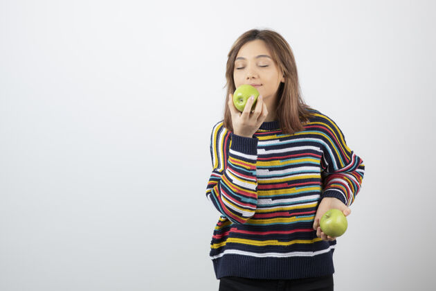 女人一个穿着休闲装的年轻女人在吃白底青苹果抱饮食休闲