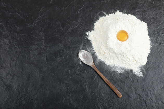 勺子用生蛋黄和面粉在黑面包表面准备面包面包房厨房鸡蛋
