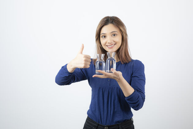 玻璃穿着蓝色上衣的美女拿着一杯水 竖起大拇指女人微笑年轻