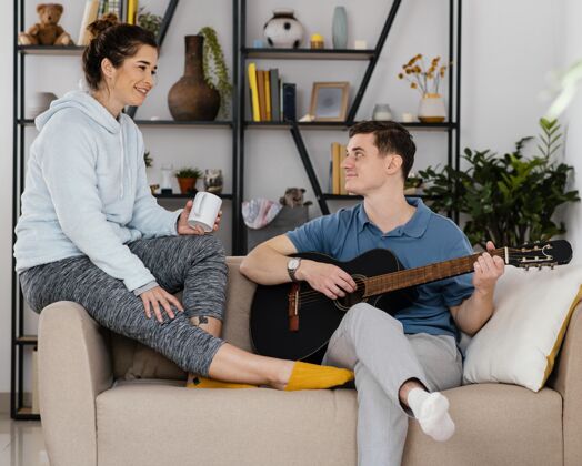 生活方式中镜头的人在沙发上用吉他水平室内室内