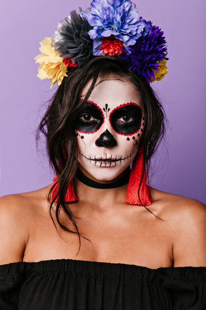 传统自信的女巫对着淡紫色的墙墨西哥女人摆着人体艺术的姿势幽灵头骨黑发