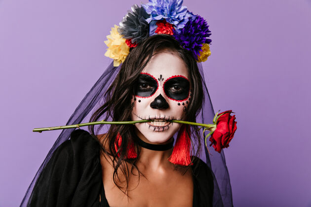 庆典热情的墨西哥女人 涂着颜料的脸 牙齿上叼着红玫瑰卷曲的深色头发 头发上开着五颜六色的花幻想传统女巫