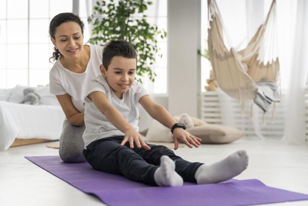 训练女人和男孩在瑜伽垫上全拍运动儿童儿童