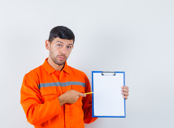 机器工业工人用铅笔指着剪贴板在制服 前视图指点钢铁制服