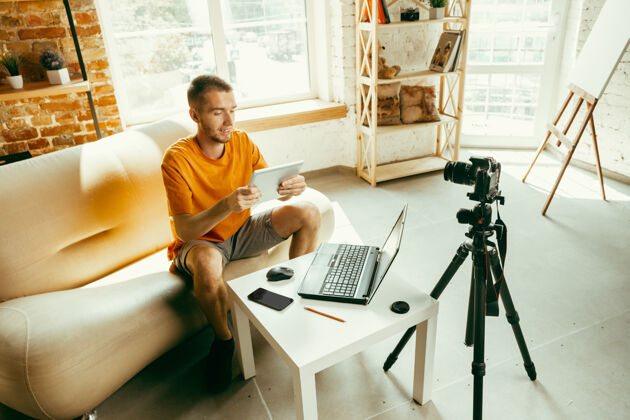 技术年轻的白人男性博主用专业相机录制视频评论家里的平板电脑虚拟博客直播现场