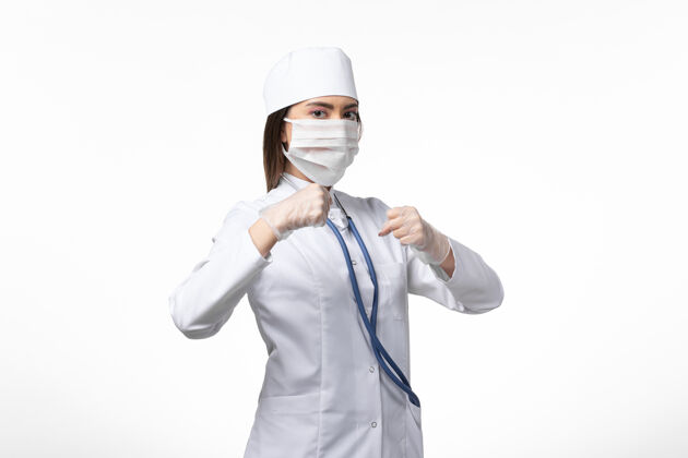 工人正面图女医生穿着白色医疗服 戴着口罩 因白墙上有冠状病毒病大流行病毒冠状病毒疾病女性套装