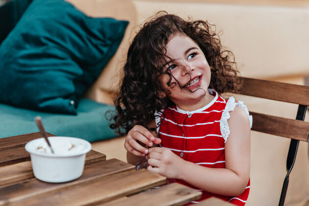 冰淇淋可爱的小女孩卷发坐在户外餐厅美丽的孩子在咖啡馆吃冰淇淋的肖像快乐咖啡馆吃
