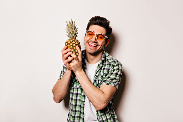 肌肉迷人的男人穿着格子装 戴着橙色眼镜 微笑着 手里拿着菠萝菠萝身体T恤