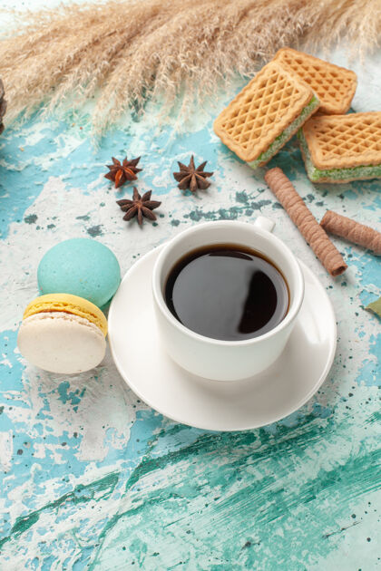 马克杯前视图华夫饼和麦卡龙配一杯茶在蓝色表面蛋糕饼干糖甜饼干视野咖啡