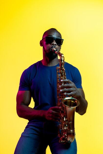 音乐年轻的非洲裔美国爵士乐音乐家用黄色吹奏萨克斯管旋律著名霓虹灯