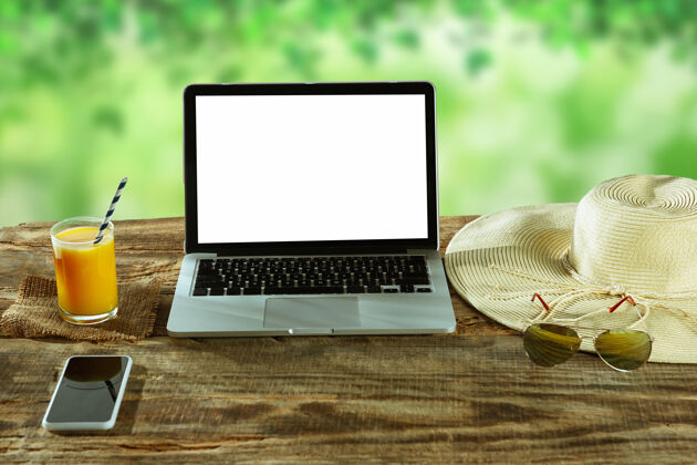 工作场所户外木桌上摆放着笔记本电脑和智能手机的空白屏幕 墙上挂着自然的眼镜 旁边是新鲜的果汁创意工作场所 商业 自由职业者的概念复制空间手机办公室室内
