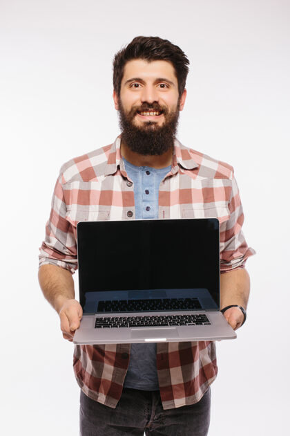 营销快乐的笑脸胡子男人拿着黑屏笔记本电脑隔着白墙电脑年轻职业