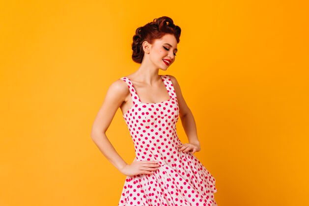 时尚穿着圆点裙的女人微笑着摆姿势浪漫的小姑娘在黄色的空间里欢笑浪漫红发漂亮