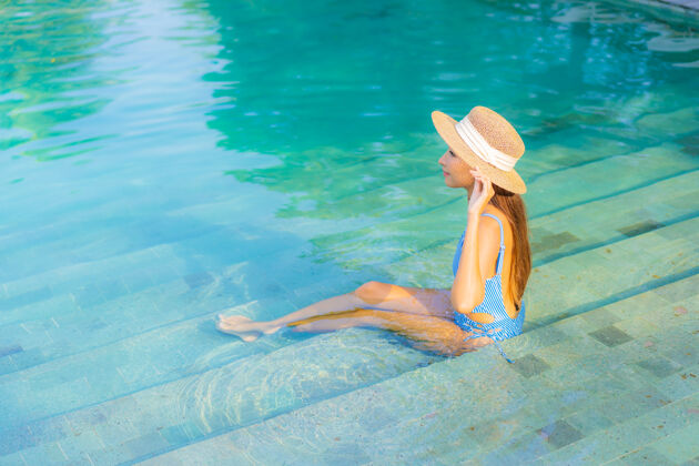 度假村肖像美丽的亚洲年轻女子放松微笑享受休闲围绕游泳池近海边度假海景酒店阳光人