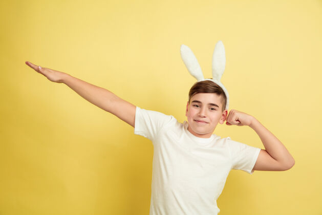 白种人复活节兔子男孩在黄色的墙上有明亮的情感庆祝面部鸡蛋