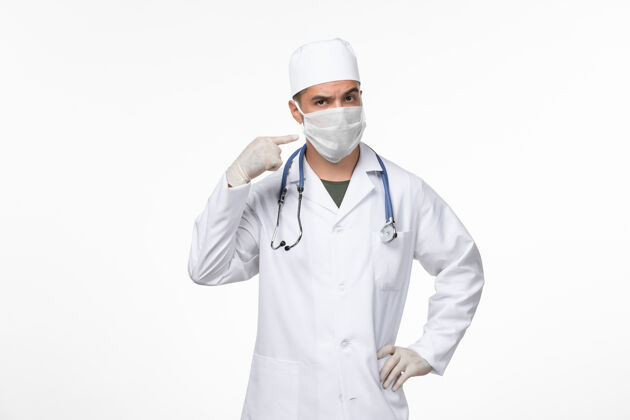 飞溅正面图：男医生穿着医疗服 戴着防病毒口罩 白墙病毒病毒-病毒性疾病大流行男性面具西装