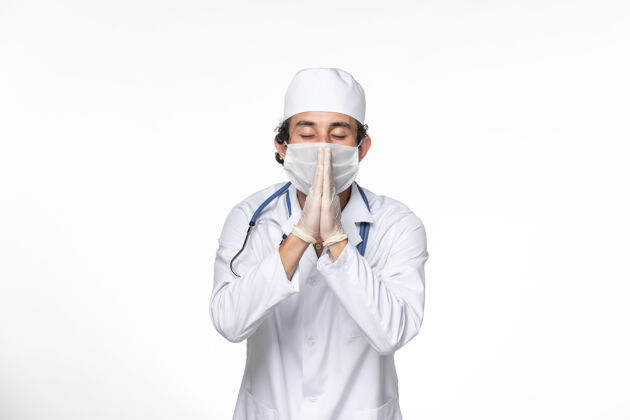 大流行正面图穿着医疗服的男医生戴着无菌口罩 以防白色桌面上的冠状病毒大流行正面消毒医疗