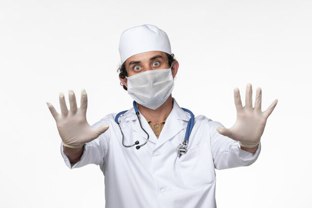 冠状病毒预防正面图：男医生穿着医疗服 戴着口罩 以防白墙病毒的传播男人正面医疗