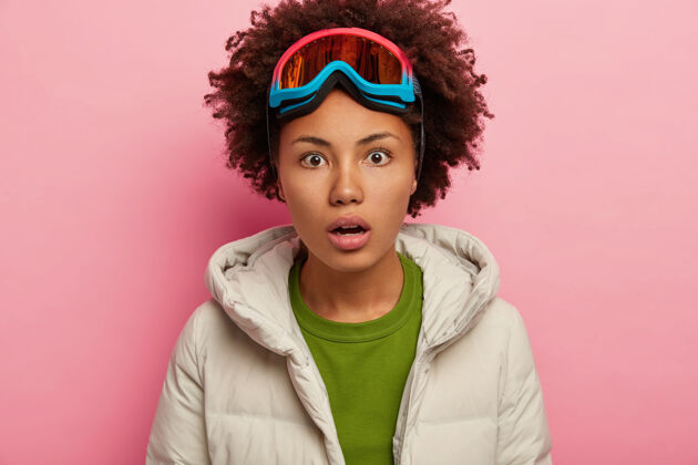 年轻穿着冬装 头上戴着滑雪面罩的年轻女子惊呆了 屏住呼吸 在粉色的背景下与世隔绝年轻极端冬天
