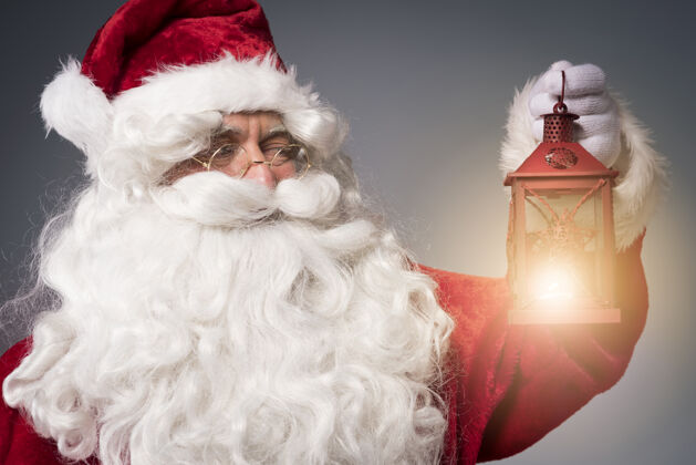 沉思圣诞老人手里拿着一盏明亮的灯笼火焰庆祝积极的情绪