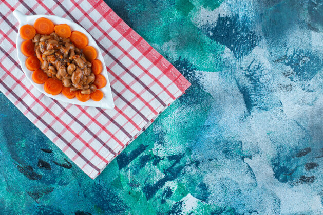 豆类把胡萝卜和豆子片放在盘子里 把茶巾放在蓝色的盘子里盘子胡萝卜美味