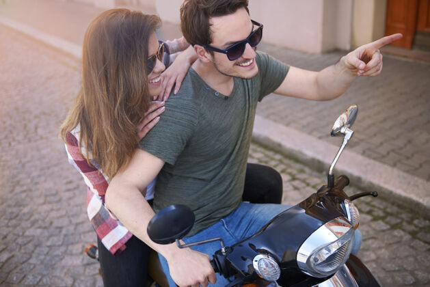 阳光一对夫妇在城里骑摩托车休闲服迷人的女人享受