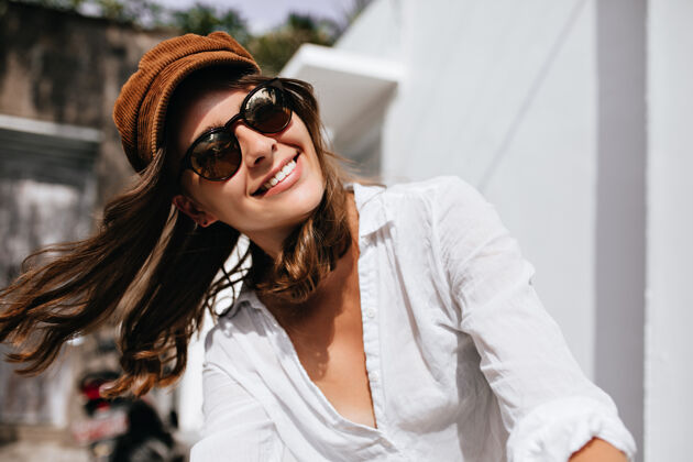 裤子在外面享受夏日阳光的女人的快照穿着时髦衬衫和帽子的女孩微笑着短发帽子华丽