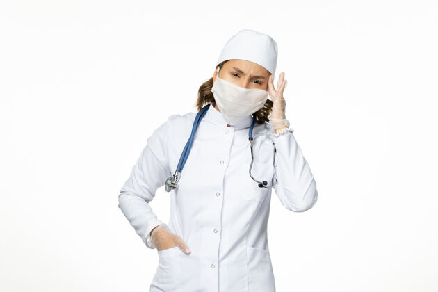 视图白壁大流行性疾病隔离冠状病毒引起头痛 身穿白色医疗服 戴口罩的女医生听诊器正面套装