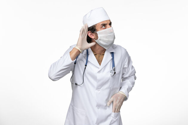 面罩正面图男医生穿着医疗服 戴着无菌口罩 以防感染柯维德病毒-试图听到白墙病毒疾病柯维德大流行疾病防护服冠状病毒正面