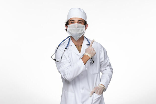 套装正面图穿着医疗服的男医生 戴着无菌口罩 以防白墙病毒感染穿着大流行正面