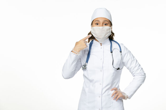 医疗正面图女医生身穿白色医疗服戴口罩因冠状病毒在白墙上大流行疾病隔离医生面具正面
