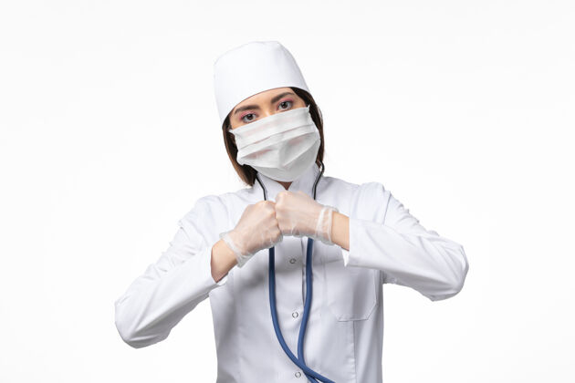 视图正面图：女医生穿着白色医疗服 戴着口罩 因大流行于白色办公桌上疾病药物病毒大流行covid-办公桌医生听诊器