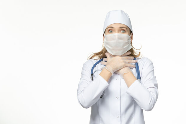 医学正面图女医生穿着医疗服 带着无菌口罩 因白墙上冠状病毒病大流行疾病冠状病毒视图冠状病毒人