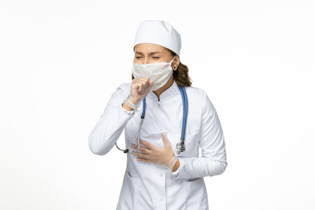 医学白衣女医生 戴着口罩 在白墙上咳嗽 是潘多米病毒病的药视图人正面