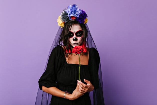 噩梦沉思的死去的新娘摆出红色的花室内拍摄优雅的白人妇女僵尸服装准备党墨西哥死亡之日恐怖