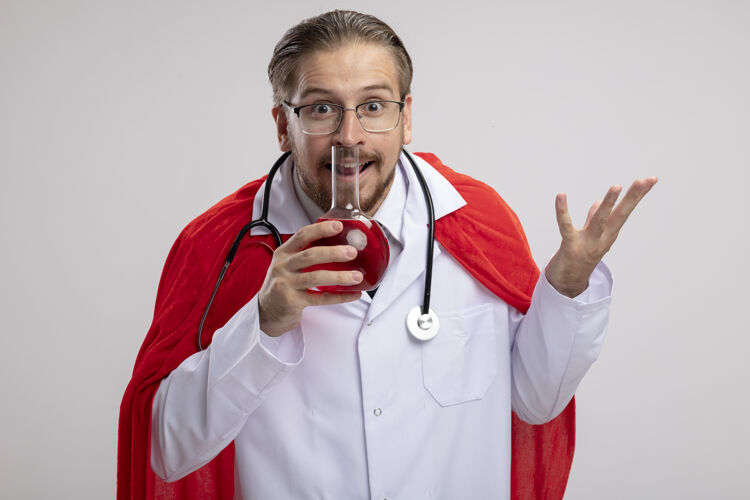 听诊器快乐的年轻超级英雄 穿着医用长袍 戴着听诊器和眼镜 手里拿着化学玻璃瓶持有手白色