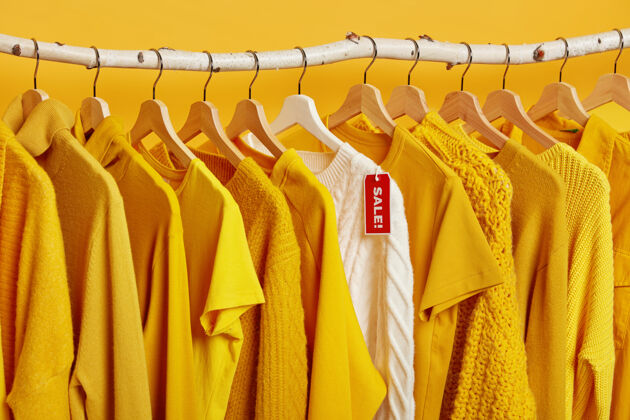 黄色服装店清仓大甩卖毛衣大折扣带标签的衣架上有针织套头衫整洁套装零售