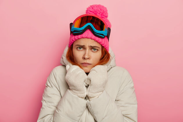 愤怒不开心生气的年轻女子不满 穿着白色保暖外套和手套 冻得发抖风帽寒冷不高兴