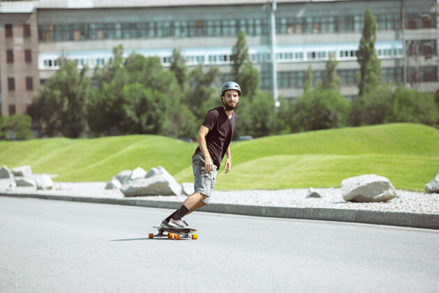 车轮在阳光明媚的日子里 滑板手在城市的街道上玩花样沥青滑板跳跃