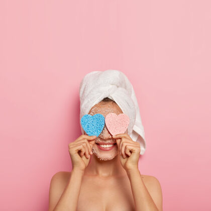 面膜快乐健康的欧洲女人的照片眼睛上放着两块海绵 掩面微笑 洗澡 裸体 粉色背景上的模特 复制空间肩膀满意女人
