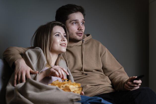 男人夫妻俩在沙发上看电视吃薯片室内女人电视遥控器