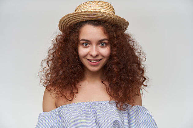 女士十几岁的女孩 快乐的女人 卷曲的姜黄色头发穿着条纹露肩衬衫和帽子微笑 特写 隔着白色的墙室内看起来特写