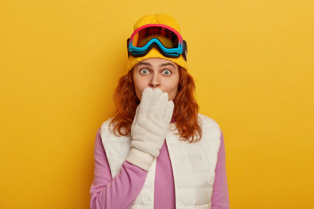 面具震惊的红发女子捂着嘴盯着镜头 穿着冬季运动专用的衣服和装备 喜欢滑雪或滑雪板 震惊运动生姜