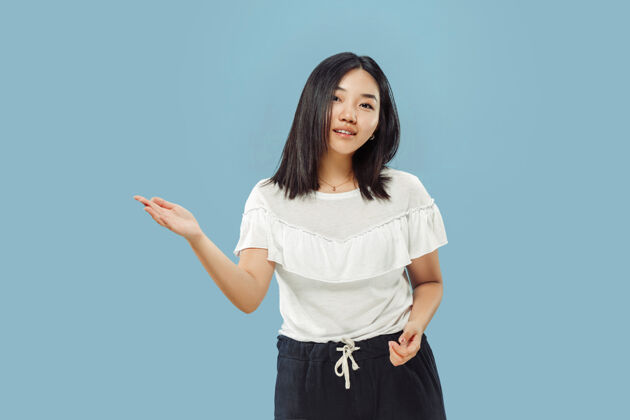 女性蓝色空间上的韩国年轻女子半身像穿白衬衫的女模特展示并指向某物手工作面部