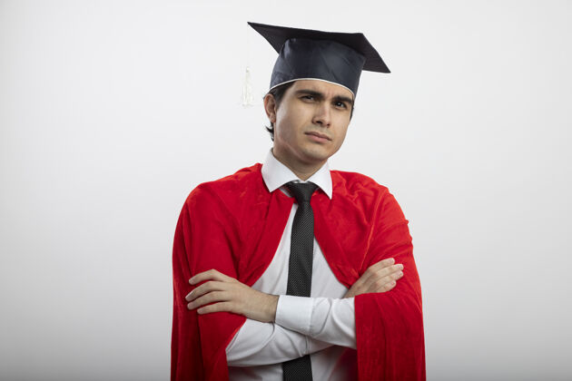 帽子自信的年轻超级英雄戴着领带和毕业帽双手交叉看着镜头年轻手穿