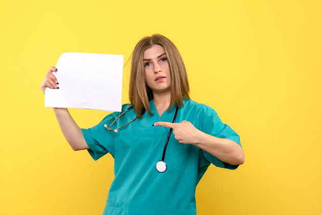 医院黄色墙上拿着文件的年轻女医生的正视图工人护士从业者